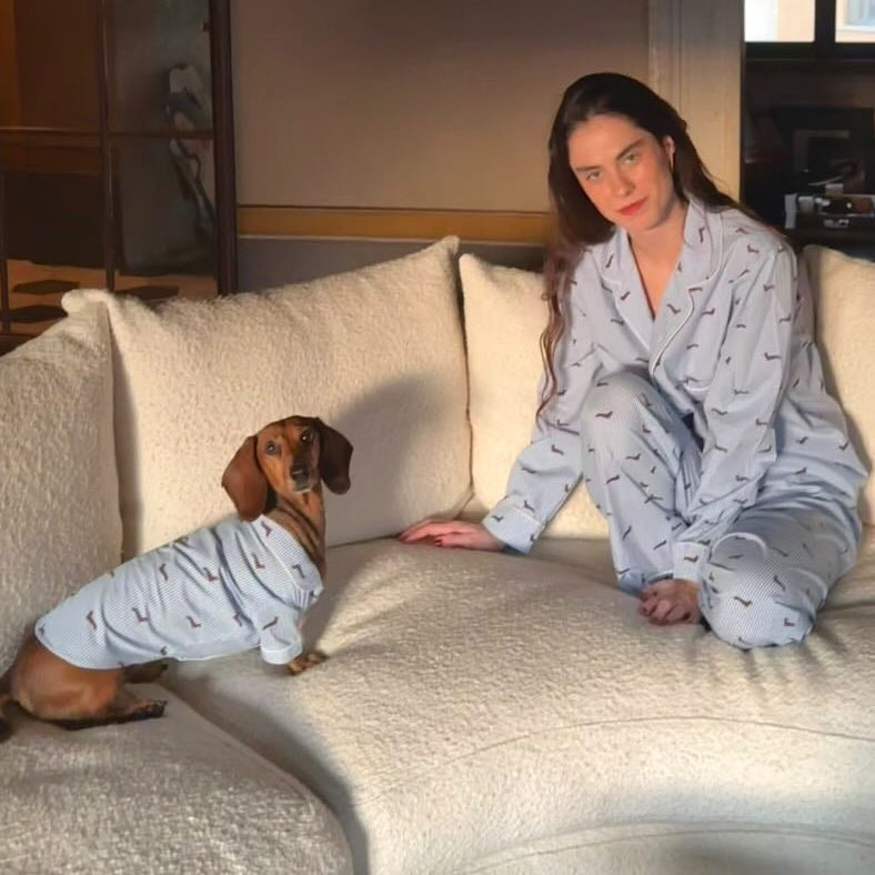 Woman and dachshund wearing matching blue-and-white pajamas