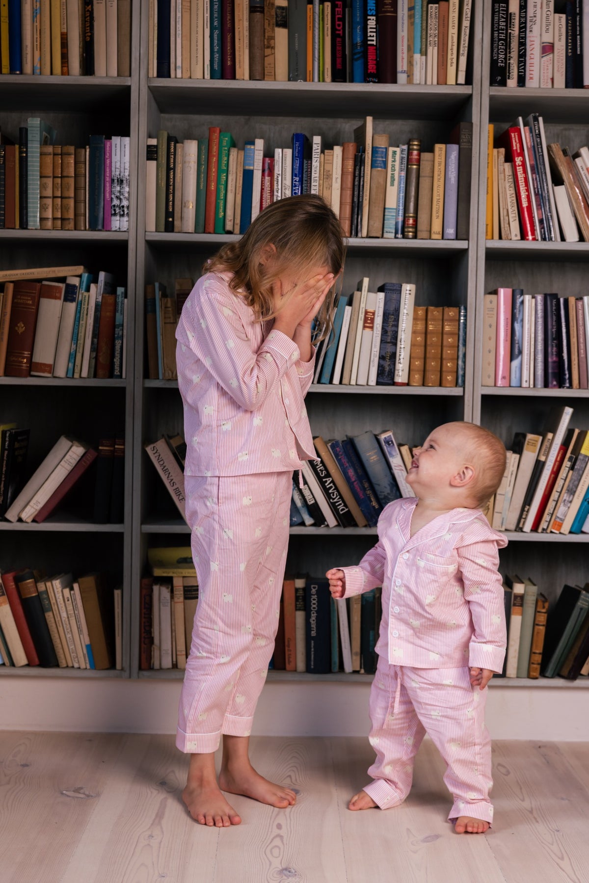 Children wearing pink and white Pomeranian pajamas in a library