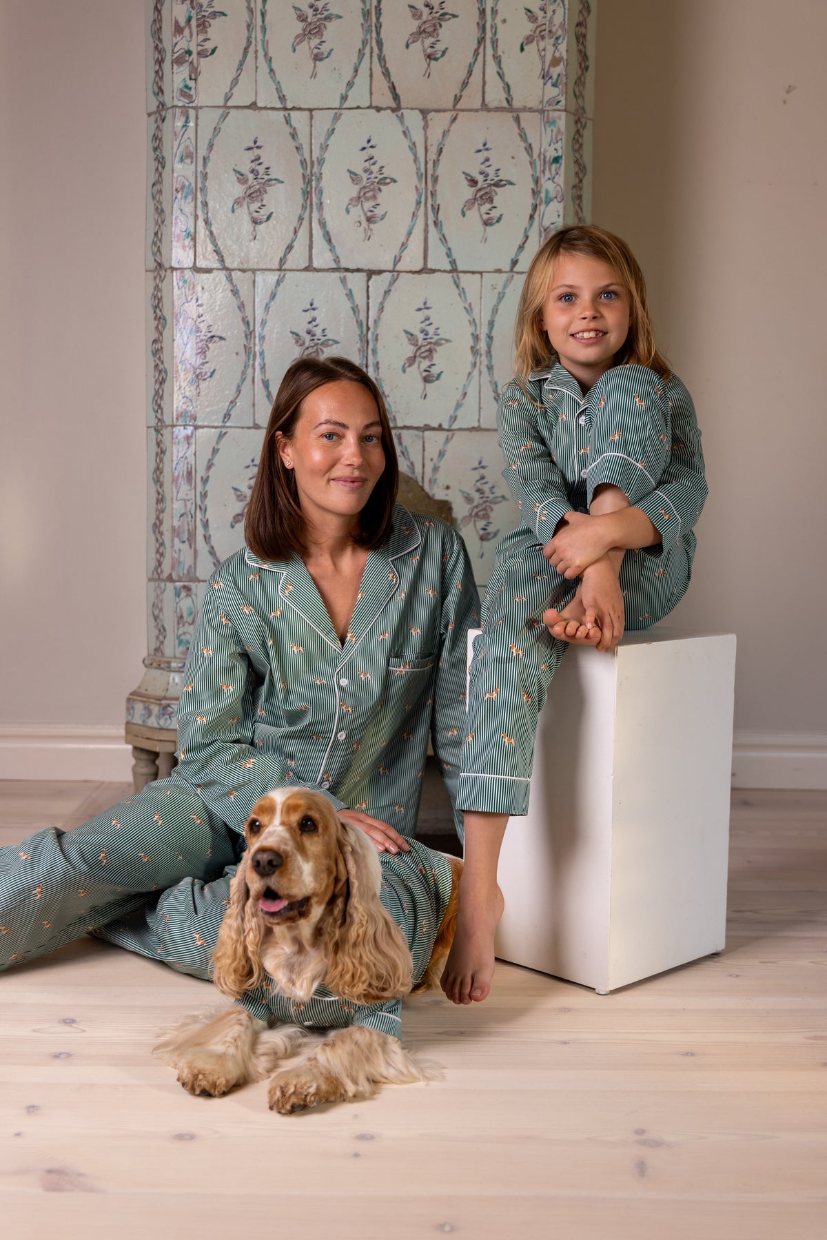 Family and Spaniel in matching green and white pajamas by the fireplace