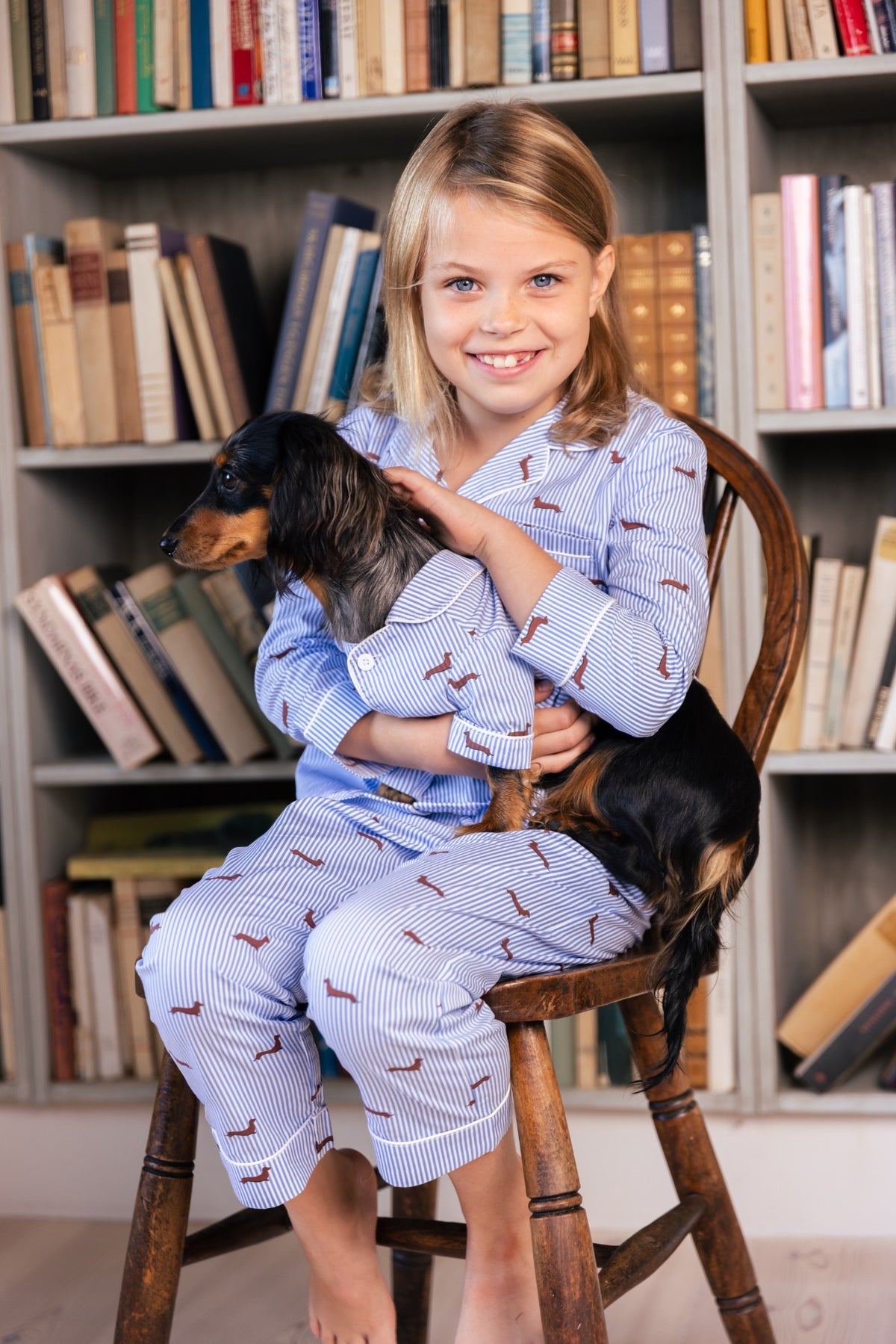 Child cuddling a Dachshund while wearing the blue and white Dachshund kids pajama