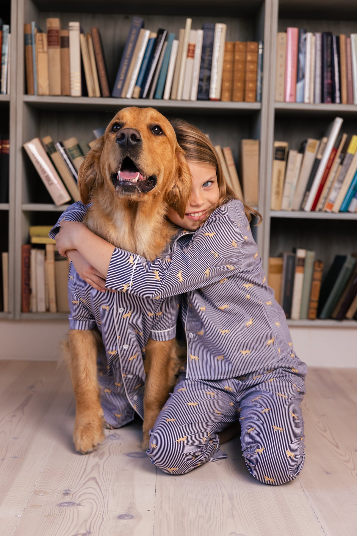 Child hugging a Golden Retriever in the navy and white Retriever kids pajama