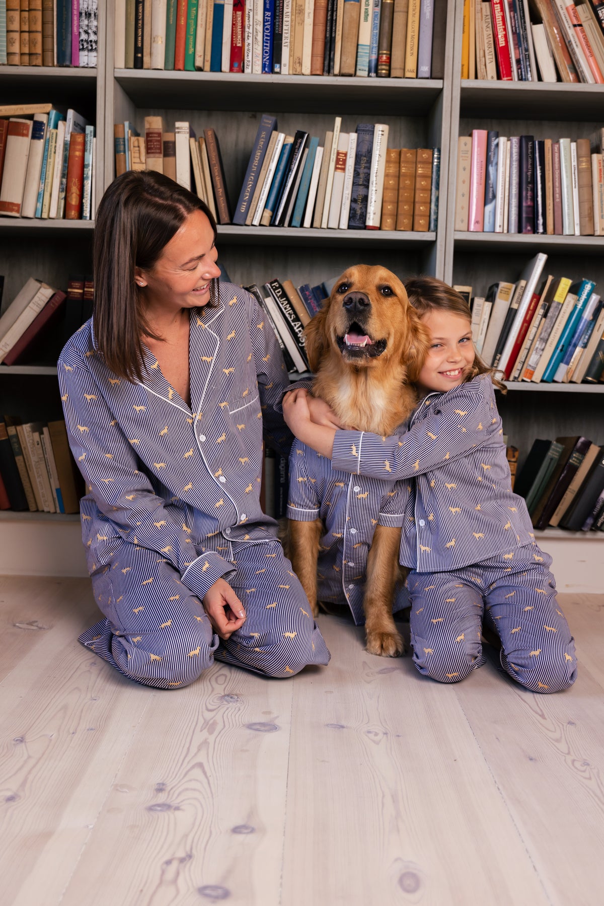 Family and Golden Retriever in matching navy and white pajamas in a library